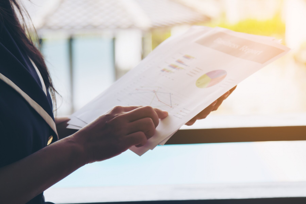 A female professional holding a pile of reports with graphs and charts